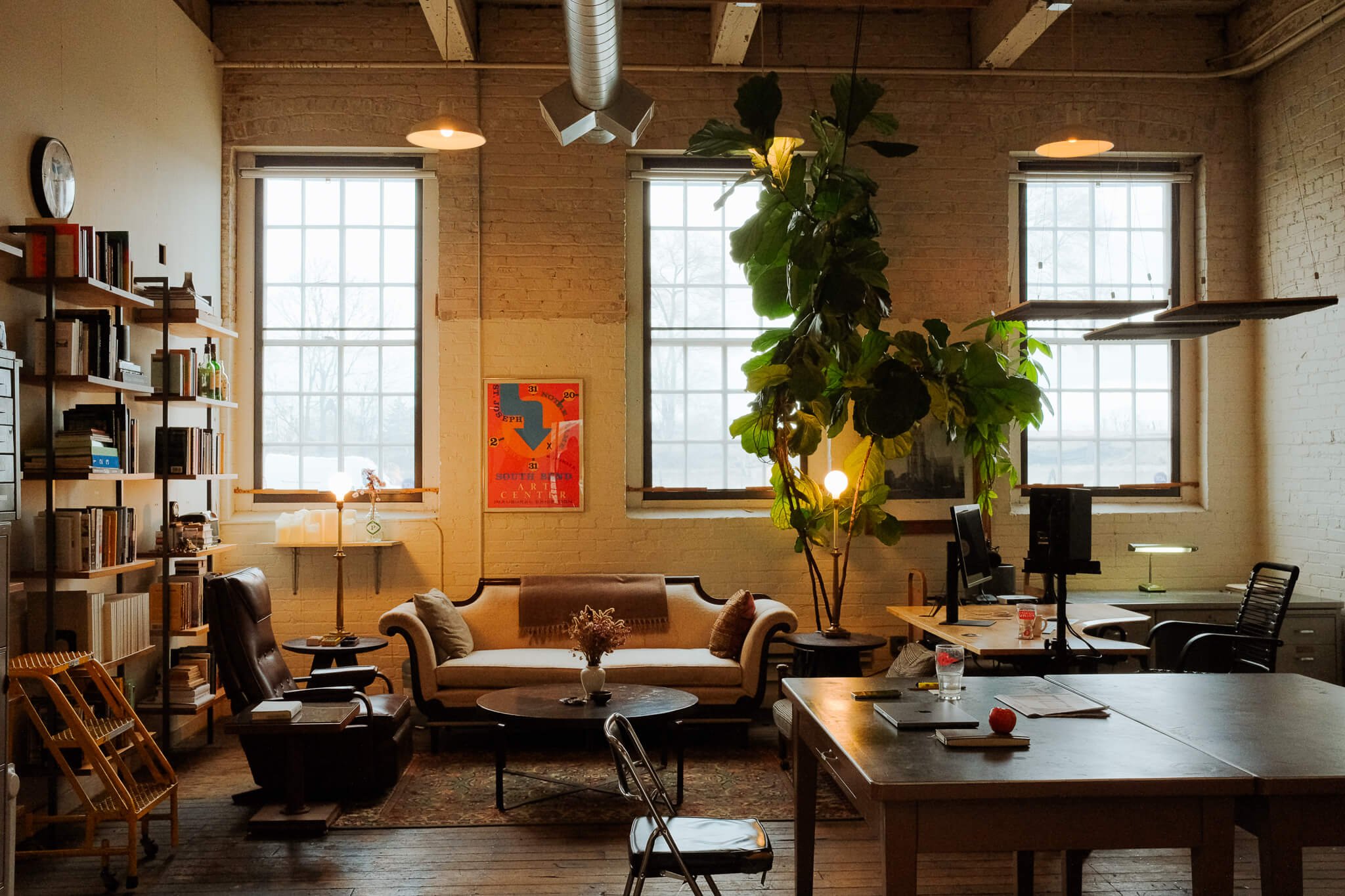Light-filled lounge and workspace inside Vested Interest, with vintage sofa, bookshelves, and tall windows.