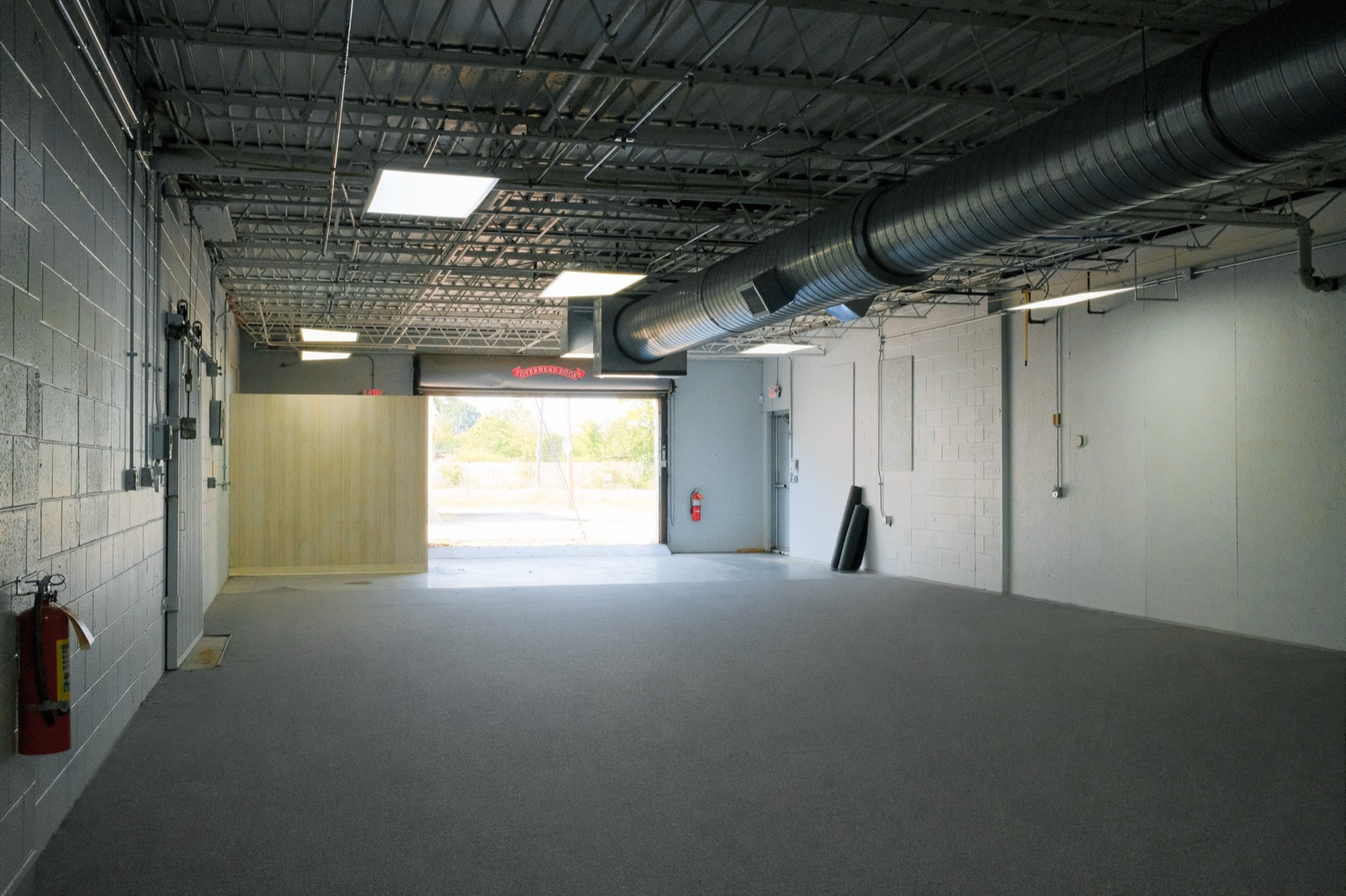 Ziker Works North with a roll-up garage door, open floor, exposed ceiling, and storage area.
